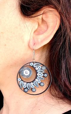 a close up of a woman's ear wearing large earrings with spiral designs on them