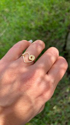 a person's hand with a gold ring on it and grass in the background