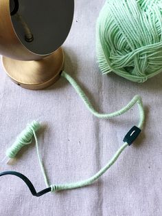 two balls of yarn sitting next to a lamp on top of a white table cloth