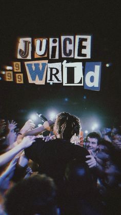 a man standing in front of a crowd with his arms out and the words juice wrld above him