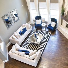 an aerial view of a living room with white couches and blue accented chairs