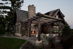 a rustic log cabin with outdoor seating and fire pit in the front yard at dusk