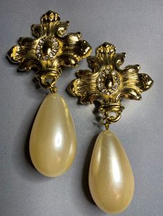 STUNNING VINTAGE 1980s BRIDAL GOLD TONE FAUX BAROQUE PEARL STYLE SPARKLING CRYSTALS MALTESE CROSS WEDDING BIG STATEMENT DANGLY CLIP ON EARRINGS !! A GORGEOUS pair of vintage 1980s dangly earrings !! These earrings feature a BEAUTIFUL glamorous style big statement faux baroque pearl , then a maltese cross with stunning sparkling CRYSTALS. Very high quality ! This pair is so unique and a TRULY eyecatching piece ! Perfect for your loved ones special wedding day or for any occasion as these earrings Vintage Statement Pieces, Statement Wedding Earrings Gold, Luxury Retro Collectible Jewelry, Vintage Gold Accessories, Luxury Baroque Earrings For Anniversary, Luxury Victorian Yellow Gold Pearl Earrings, Luxury Yellow Gold Victorian Pearl Earrings, Vintage White Bridal Earrings For Party, Vintage White Bridal Earrings For Weddings