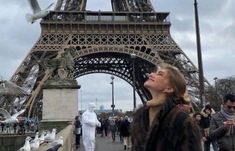 a woman standing in front of the eiffel tower with birds flying around her