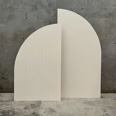 an arch shaped sculpture sitting on top of a cement floor next to a wall with two doors