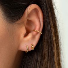 a close up of a person's ear wearing gold earrings