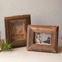 two wooden frames sitting on top of a table next to a plant and pencils