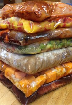 a pile of food wrapped in plastic sitting on top of a wooden table