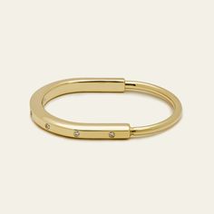 The Tiffany & Co Lock Bangle is all about bringing people together, and this bangle is a bold symbol of those personal connections that shape us. It's made for everyone, no matter your gender, and it has this cool clasp that's like a padlock, inspired by Tiffany's history. The bangle is crafted in 18k yellow gold and has sparkly diamonds for a touch of contrast. With a total carat weight of 0.31 and a medium size fitting wrists up to 6.25 inches, this Tiffany Lock Bangle is a simple, stylish way Stackable Open Ring Bracelets For Everyday, Modern 14k Gold Hoop Bracelets, Modern Adjustable Hoop Cuff Bracelet, Everyday Yellow Gold Open Ring Bracelets, Everyday Yellow Gold Open Ring Bracelet, Polished Bangle Bracelet For Promise Occasion, Adjustable Open Ring Yellow Gold Bracelet, Modern Stackable Bangle Jewelry, Modern 14k Gold Hoop Bangle