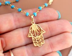 "This is a gorgeous multi-strand necklace made of 3mm faceted Turquoise gemstones on 24kt gold veril. Necklace layers measure 16\"-18\" or 18-20\" with a 18kt gold filled Hamsa pendant that measures 3/4\". Beautiful gold rose beads accent this lovely necklace. Necklace comes nicely boxed for the perfect gift! Turquoise absorbs negativity, promotes honest & clear communication from the heart & is an excellent grounding stone. Good for healing the spirit & soul, it is known as a master Handmade Dainty Gold Turquoise Necklace, Dainty Handmade Gold Turquoise Necklace, Gold Turquoise Necklace With Lobster Clasp, Gift, Spiritual Turquoise Necklace With Lobster Clasp, Gold Turquoise Necklace With Round Beads As A Gift, Gold Turquoise Necklace With Round Beads For Gift, Gold Turquoise Necklace With Tiny Beads In Bohemian Style, Bohemian Gold Turquoise Necklace With Tiny Beads, Gold Bohemian Turquoise Necklace With Tiny Beads