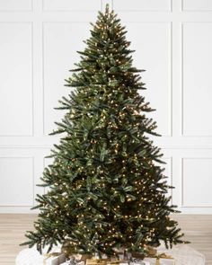 a small christmas tree with presents under it on a white plate and wood flooring