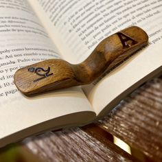 a wooden bookmark with the letter a on it sitting in front of an open book