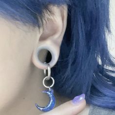 a close up of a person with blue hair wearing ear rings and piercings on their ears