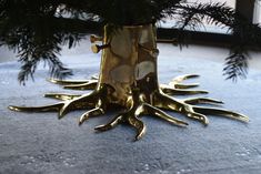 a gold vase sitting on top of a blue rug next to a christmas tree branch