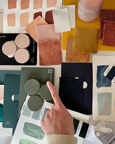 a person is pointing at some paint samples