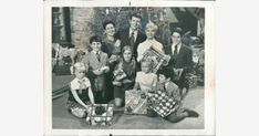 an old black and white photo of people holding presents