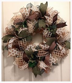 a wreath with burlocks and bows hanging on a door handle, decorated with leaves