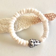 "Natural white Hawaiian puka shell and Hebrew cone shell stretch bracelet. Genuine white smooth polished 8mm puka shell stretch bracelet accented with authentic Hawaiian Hebrew cone shell. Lovely puka shells are found throughout the Islands of the Pacific. Hawaiian Hebrew cone shell with it characteristic brown and white pattern is found on Hawaii's North Shores. Pukas are natural with normal imperfections from the pounding surf. Stretch bracelet is made to order. Please add 3/4\" to 1\" to actu White Coastal Beaded Bracelets For Vacation, White Coastal Style Bracelet For Gift, White Coastal Beaded Bracelets For Beach, White Adjustable Stretch Bracelet With Beachy Style, Coastal White Beaded Bracelets For Gift, Adjustable White Stretch Bracelet With Beachy Style, Adjustable White Coastal Beaded Bracelets, Coastal Style White Bracelets For Vacation, Beachy White Stretch Bracelet For Vacation