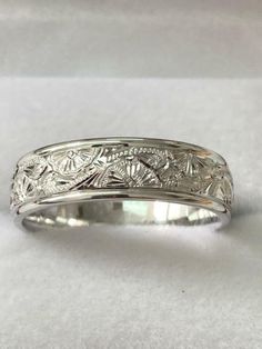 a wedding band with flowers and leaves engraved on the side in white gold or silver