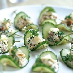 cucumber bites are topped with cheese and herbs on a white plate, ready to be eaten