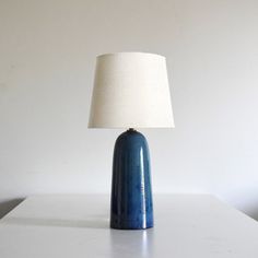 a blue table lamp sitting on top of a white counter next to a light bulb