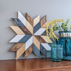 two vases with flowers are sitting on a shelf next to a wooden star decoration