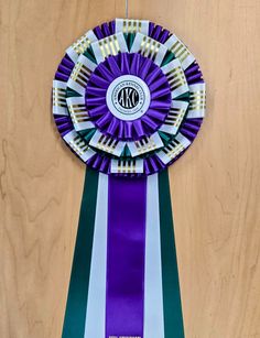 a purple and green award ribbon on top of a wooden table