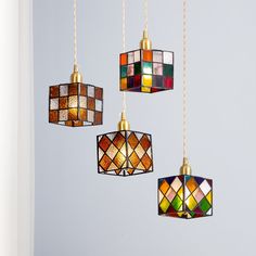 four multicolored stained glass lights hanging from gold chains in a room with light blue walls