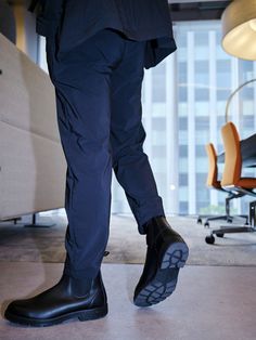 a man in black rain boots standing next to an office chair