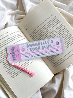 an open book with a tassel on top of it next to a pink bookmark