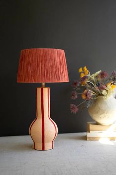 a lamp that is sitting next to a vase with flowers