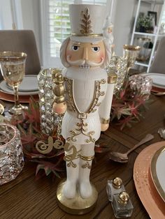 a white and gold nutcracker figurine sitting on top of a wooden table