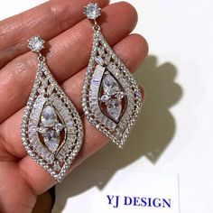 a pair of diamond earrings is being held by someone's hand