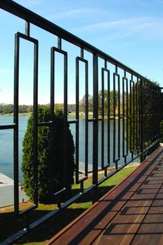 a wooden deck with black iron railings next to water