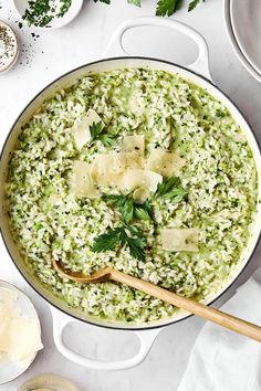 a pot filled with rice and parsley on top of a table next to other dishes