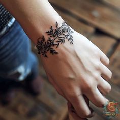 a woman's hand with a black flower tattoo on the left side of her wrist