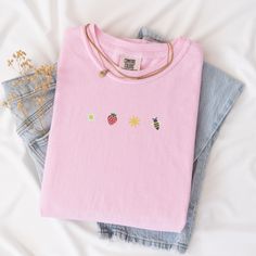 Welcome the sunny days with our Sunkissed Strawberry and Bee Embroidered T-Shirt! Made from 100% cotton Soft Comfort Colors, this shirt is both stylish and comfortable, perfect for your summer adventures.Features:Material: 100% cotton Soft Comfort ColorsSizes: S, M, L, XL, 2XL (refer to size chart in images)Colors Available: Banana, Bay, Blossom, Chalky Mint, Chambray, Ivory, Orchid, Peachy, Violet (Note: Colors may vary slightly due to monitor settings)Design: Summer-inspired embroidery featuring a daisy, strawberry, sun, and bee on the center chestCare Instructions: Machine wash cold, tumble dry lowThis Sunlissed Strawberry and Bee Embroidered T-Shirt is a delightful addition to your wardrobe, bringing a touch of sunshine wherever you go. Perfect for picnics, beach days, or casual outing Trendy Embroidered Summer T-shirt, Pink T-shirt With Embroidered Text For Summer, Pink Embroidered T-shirt For Summer, Pink Embroidered Cotton T-shirt, Pink Summer Top With Embroidered Text, Pink Tops With Embroidered Text For Summer, Pink Top With Embroidered Text For Summer, Summer Everyday T-shirt With Embroidered Text, Pink Summer Tops With Embroidered Graphics