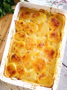 a casserole dish with cheese and meat in it on a wooden table next to parsley