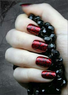 a woman's hand with red and black nail polishes on her nails, holding beads