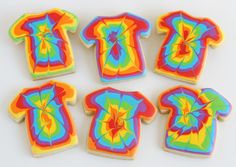 six decorated cookies in the shape of t - shirts on a white table with colorful icing