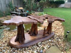 two wooden benches sitting on top of a pile of rocks next to a small pond