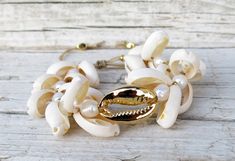 This beautiful cowrie set bracelet is made with natural white cowrie shells, natural gold cowrie shells, big 24k gold plated cowrie shell, freshwater pearls, 24k gold plated beads and beige silk cord. Bead size: shell 1,5 - 2 cm / 0,6 - 0,8 inch.; gold shell 2,5 cm/ 1 inch.; gold plated beads 0,3 cm /0,1 inch. Your bracelet comes gift wrapped and shipped via priority registered air mail with tracking info available. Feel free to ask me any questions! Thanks for visiting and happy shopping :) Handmade White Pearl Bracelet For Vacation, Cowrie Shell Beaded Bracelets As Gift, White Oyster Bracelet Jewelry For The Beach, White Oyster Bracelet Jewelry For Vacation, White Shell Pearl Bracelet For Beach, White Shell Pearl Bracelet For The Beach, White Cowrie Shell Bracelet, Gold Cowrie Shell As Gift, Bohemian Gold Beaded Bracelets With Shell