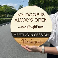 a woman holding up a sign that says, my door is always open except right now meeting in session thank you