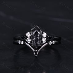 a black and white diamond ring with three diamonds on the side, in front of a dark background