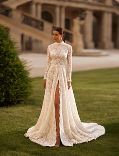 a woman in a long sleeved wedding dress standing on the grass with her legs slited