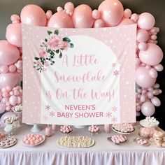 a baby shower sign surrounded by pink balloons and desserts on a white table cloth