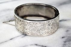 Antique sterling silver hinged bangle bracelet from the late Victorian Era. The front is hand engraved with swirling ivy leaves. The design extends a little bit to the back side of the bracelet for a little extra detail. Era: Victorian Markings: None Material: Sterling Silver (acid tested) Measurements: 24.5 mm wide 58mm x 46.2mm Condition: Good antique condition with minor wear from age. A few dings and dents on the back. Hinge works well. Safety chain is intact. Shipping is free in the United Ivy Leaves, Sterling Silver Locket, Ivy Leaf, Garnet Bracelet, Safety Chain, Silver Lockets, Heart Locket, Hinged Bangle, Crystal Heart