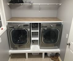 a washer and dryer in a small room with open shelves on the wall