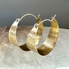 These sweet, wide brass hoops make great "every day" earrings. Hammered and oxidized, sterling ear wire fits into hole in back of hoop to close. Small - around 3/4" diameter Medium - 1 1/2" diameter Large - a little over 2" diameter Hand Forged Bronze Small Hoop Jewelry, Oxidized Finish Hoop Earrings As Gift, Oxidized Round Hoop Earrings As Gift, Bronze Hammered Hoop Earrings, Bronze Hand Forged Hoop Earrings, Bronze Brass Hoop Earrings With Ear Wire, Hand Forged Bronze Hoop Earrings, Hand-forged Bronze Hoop Earrings, Bronze Ear Wire Hoop Earrings In Brass