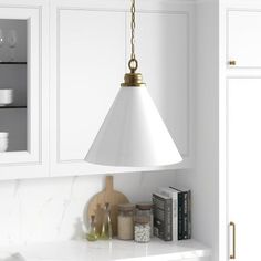 a kitchen with white cabinets and a gold pendant light hanging from the ceiling above it